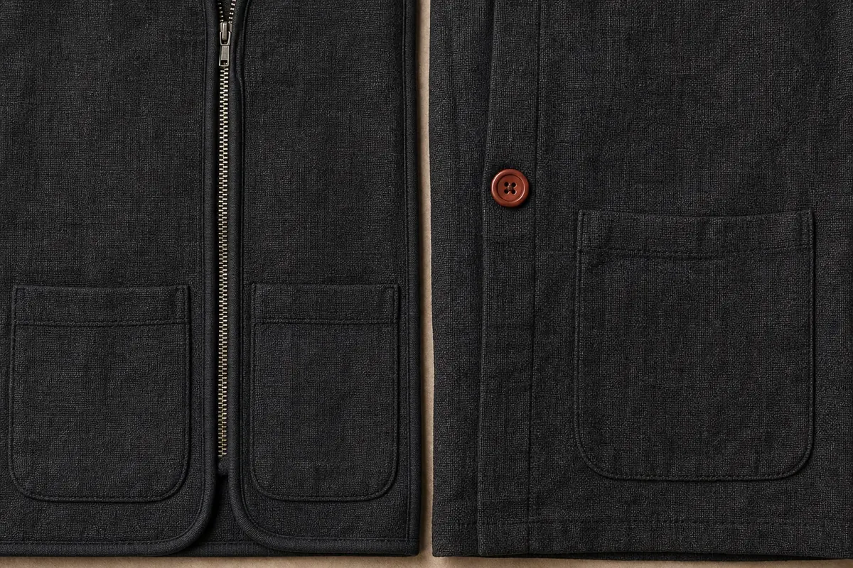 Two dark panels, one carrying a zip, piped edges and a double patch pocket, the other a single plain pocket and one button