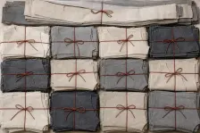One bundle of a single style's cut parts tied with rust-red thread, and below it twelve more bundles laid out in rows