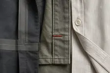 Three constructions side by side in macro: a welded and taped sportswear seam, a bar tack stitched in rust-red through workwear canvas, and a fine shirting placket with its buttons