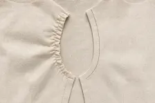 Two calico bodice fronts, the left with its armhole gathered and puckered, the right with the same seam lying smooth beside a rust-red stitch line
