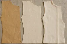 The same bodice front in three states at one size: a brown paper pattern piece with punched holes and drill marks, the same shape cut in calico with raw edges, and the same shape sewn with its seam pressed open and a rust-red stitch at the shoulder
