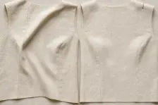 Two calico bodice fronts, the left with a fold dragging from the shoulder and a hem that rises at one side, the right level under a rust-red shoulder stitch