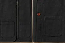 Two dark panels, one carrying a zip, piped edges and a double patch pocket, the other a single plain pocket and one button